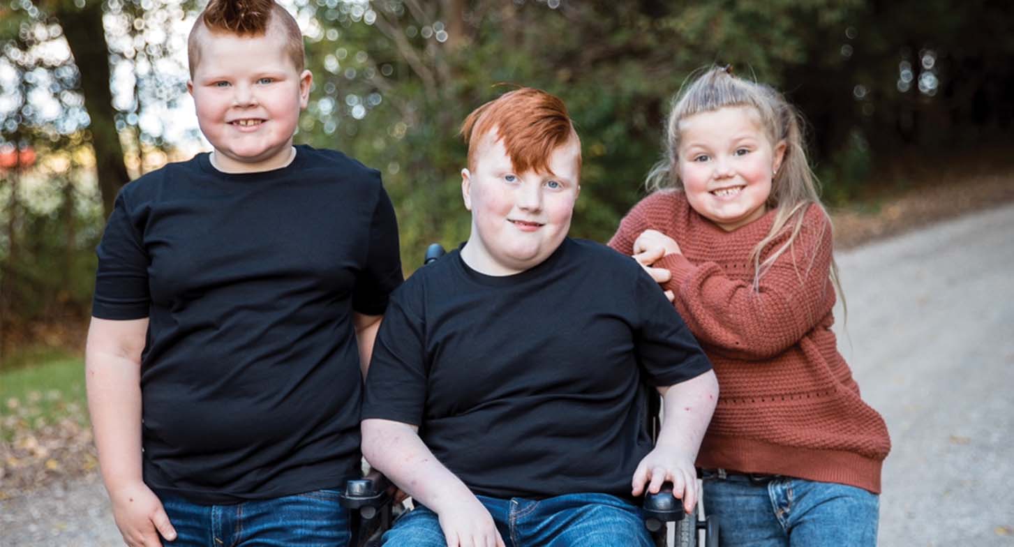 Seth in a wheelchair with his siblings beside him.