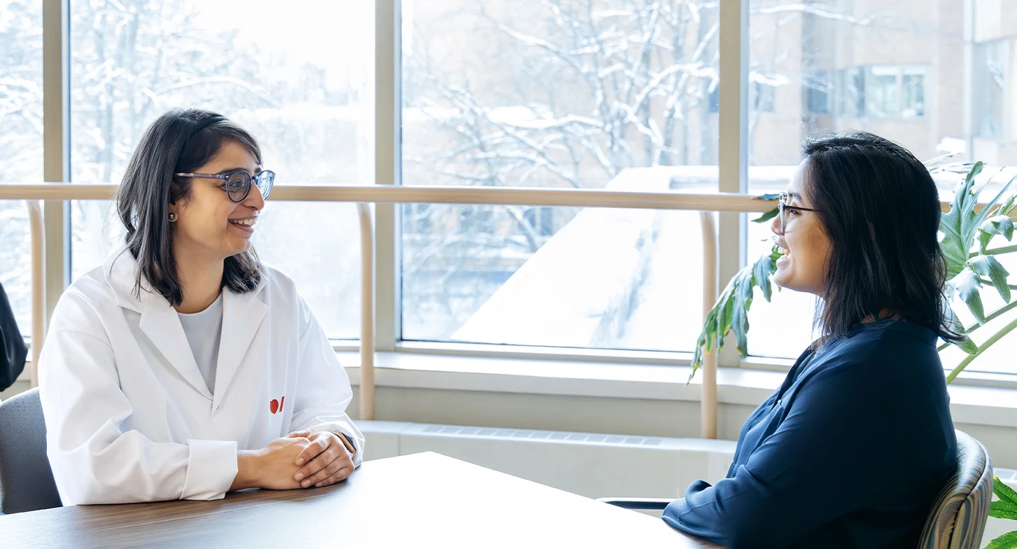 Dr. Swati Mehta with her PhD student sitting by a table sharing a conversation.