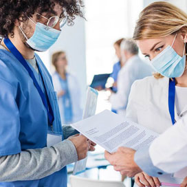 A group of medical professionals in masks look at a paper.