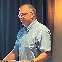 Scott Harper standing at a podium addressing an audience