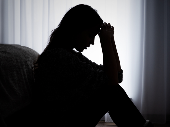 A person appearing to be stressed sitting alone in a dark room