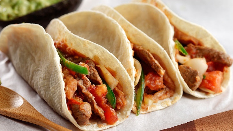 Three tortillas filled with steak, red and green peppers and salsa
